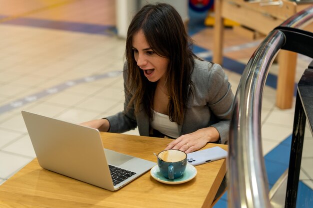 Empresária surpresa lendo notas no netbook no café