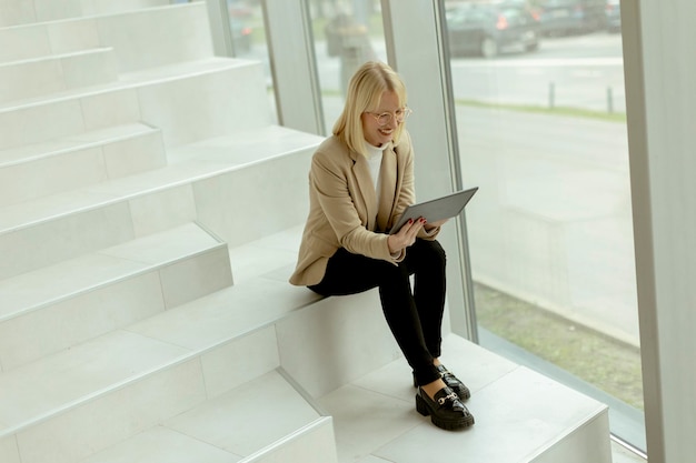 Empresaria con tableta digital en las escaleras de la oficina moderna