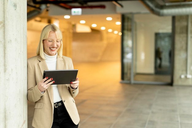 Empresaria con tableta digital en el pasillo de la oficina moderna