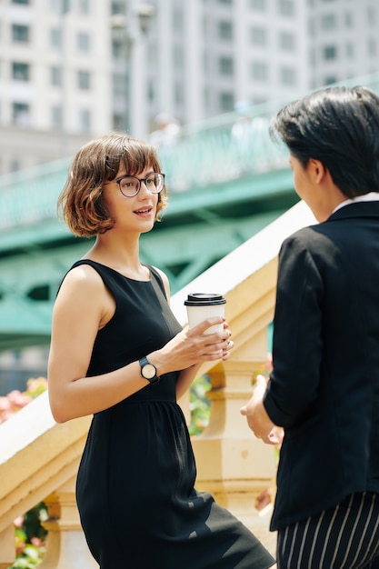 Empresaria con taza de café hablando con colega