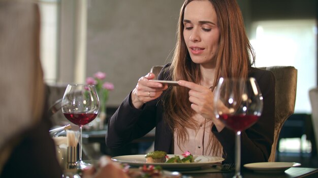 Empresária tirando foto de comida em smartphone no restaurante
