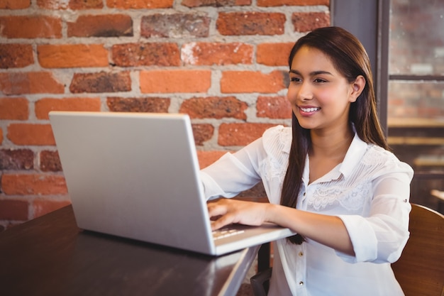 Empresaria tomando un café y trabajando en la computadora portátil