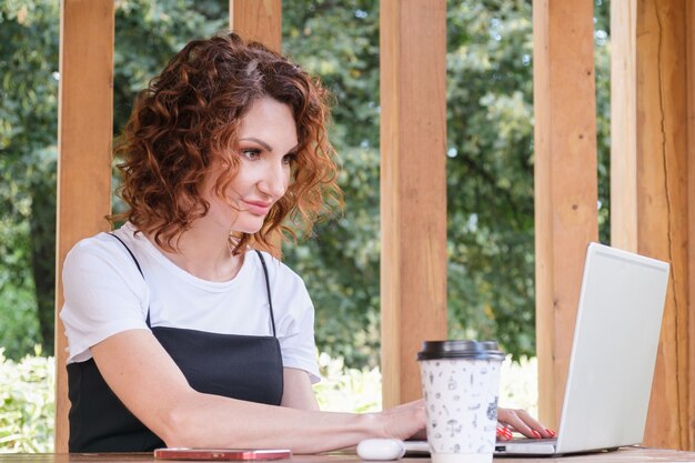 La empresaria trabaja en una computadora portátil en un espacio de coworking en un parque de la ciudad.