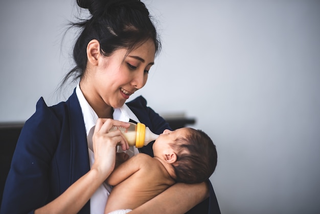 Empresaria trabajando desde casa, sosteniendo una niña