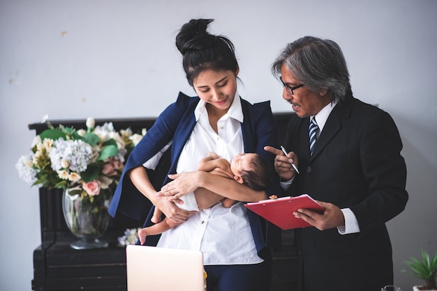 Empresaria trabajando desde casa, sosteniendo una niña