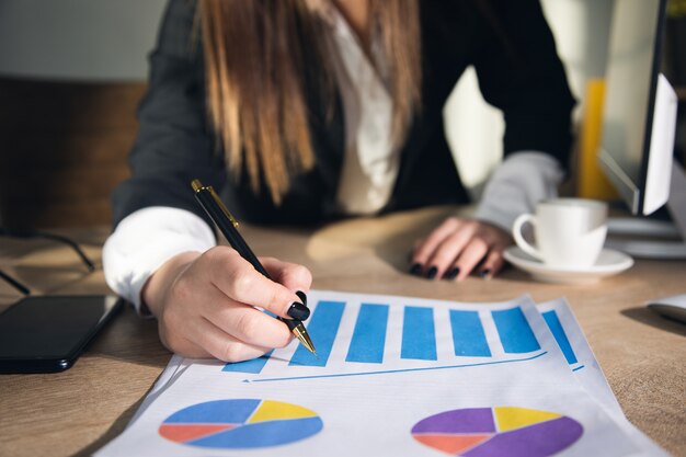 Empresaria trabajando con gráficos y tablas en la oficina.