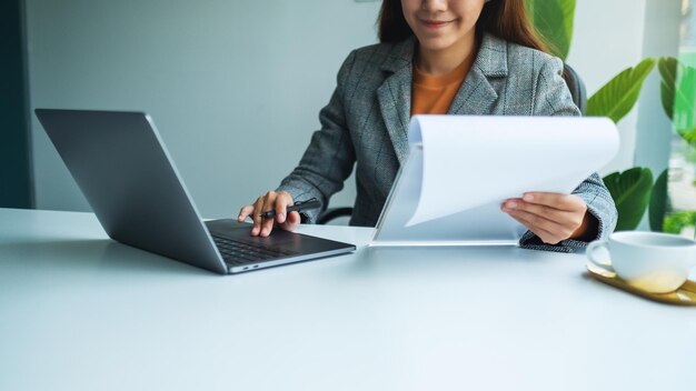 La empresaria trabajando en el papeleo financiero y un ordenador portátil en la oficina