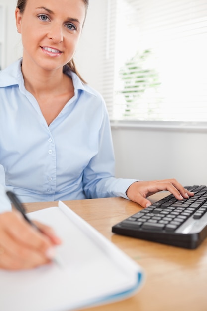 Foto empresaria de trabajo morena sentada detrás de su escritorio mirando i