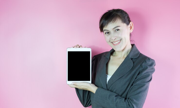 Empresaria en traje sonriendo y mostrando tableta.