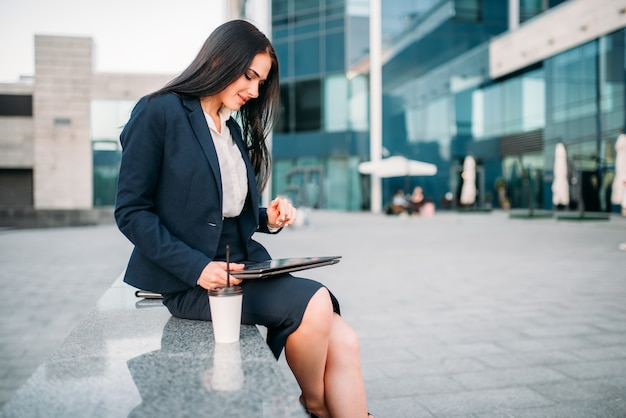 La empresaria en traje trabaja en el portátil al aire libre