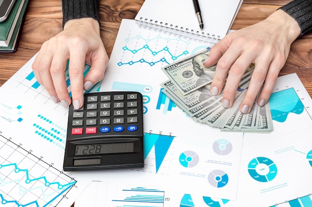 Empresária usa calculadora para calcular índices financeiros da empresa no local de trabalho Conceito de negócios