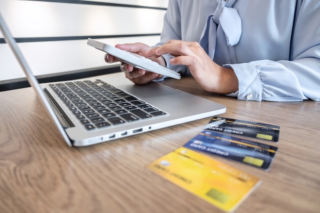 Foto la empresaria usando una computadora portátil y sosteniendo una tarjeta de crédito para pagar la pantalla de la página de detalles compras en línea