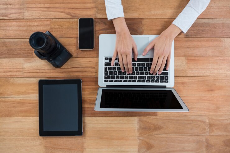 Foto empresaria usando laptop con cámara, tableta digital y teléfono móvil