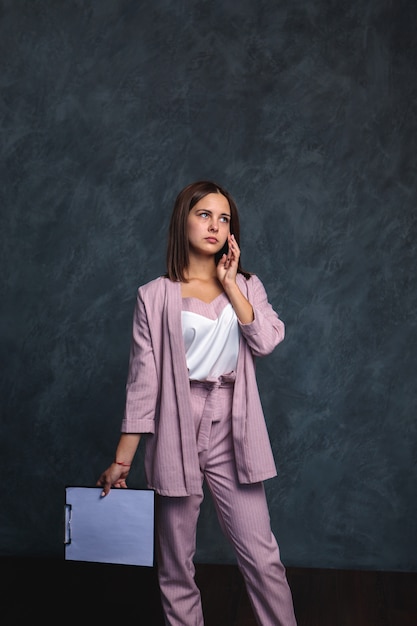 Empresária, vestindo terno roxo, segurando a pasta e ligar pelo telefone móvel