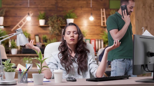 Empresaria zen relajada con los ojos cerrados sentado en el escritorio en posición de yoga meditando durante la pausa de trabajo en la oficina de la empresa de inicio. Trabajador emprendedor concentrado en la respiración