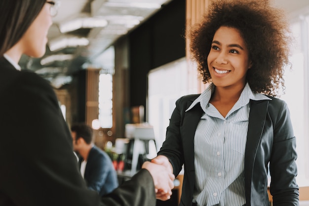 Empresárias asiáticas e afro-americanas está agitando as mãos.