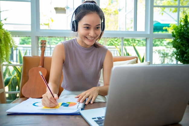 Las empresarias asiáticas usan computadoras portátiles y usan audífonos para reuniones en línea y para trabajar desde casa.