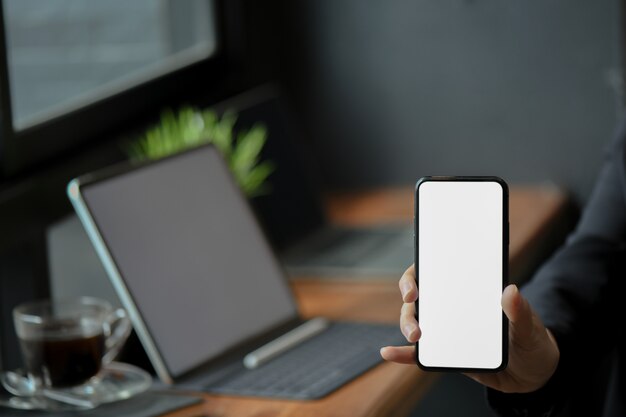 Las empresarias dan mostrar la pantalla en blanco del teléfono móvil en la oficina.