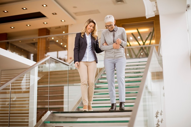 Empresarias mayores y jóvenes bajando las escaleras