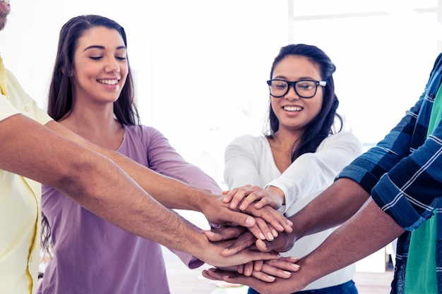 Foto empresarias que apilan las manos con el equipo mientras que se coloca en oficina creativa