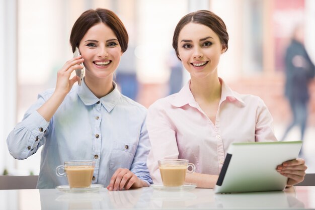 Empresarias sentadas en café urbano y usando tableta digital