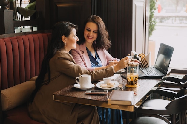 Empresárias sentam-se em um café bebem café e conversam sobre negócios, discutem negócios e se divertem