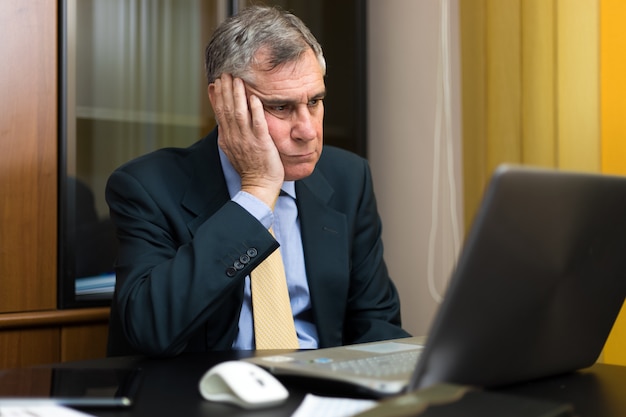 Empresario aburrido frente a su computadora portátil