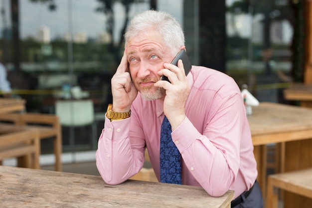 Empresario aburrido hablando por teléfono en café