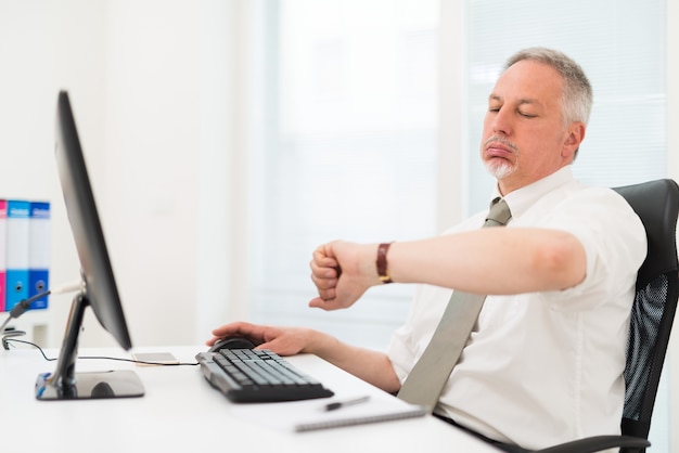 Foto empresario aburrido mirando su reloj