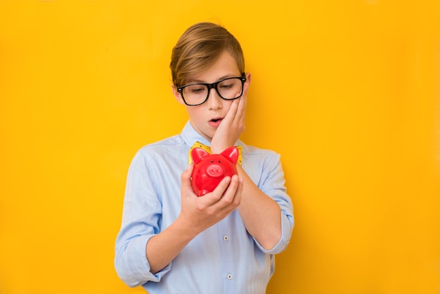 Empresario. Adolescente sorprendido sosteniendo una hucha roja. Concepto de negocio. Concepto de ahorro de dinero. Publicidad bancaria. Hucha. Bancarrota financiera