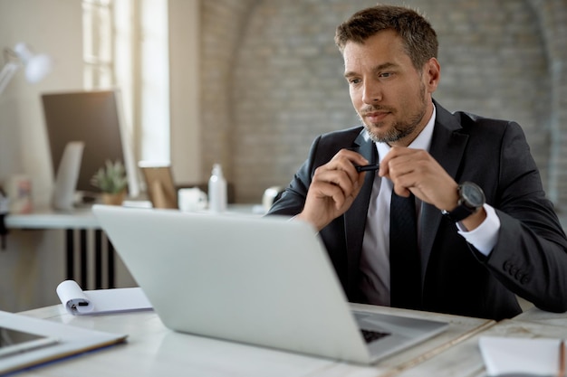 Empresário adulto médio usando computador enquanto trabalhava em sua mesa de escritório