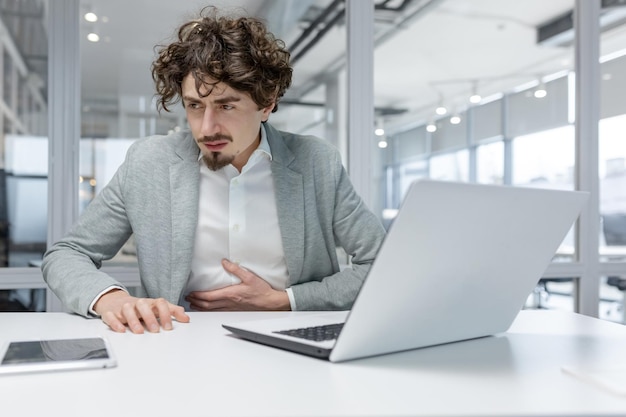 Empresario adulto que se siente mal en su lugar de trabajo en una oficina moderna que muestra el trabajo típico de oficina