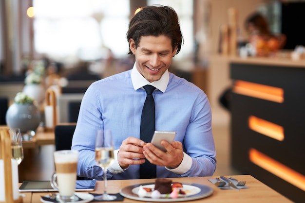 Empresario adulto con smartphone en el almuerzo en el café