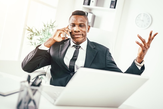 Empresario africano pensativo hablando por teléfono inteligente en la oficina moderna.