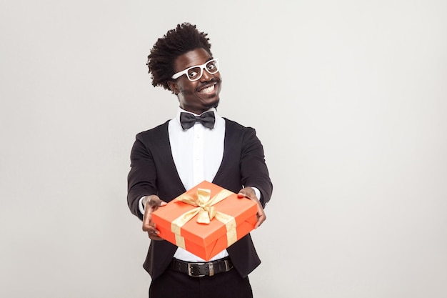 Empresario africano romántico mostrando caja de regalo para el día de san valentín. Disparo de estudio.