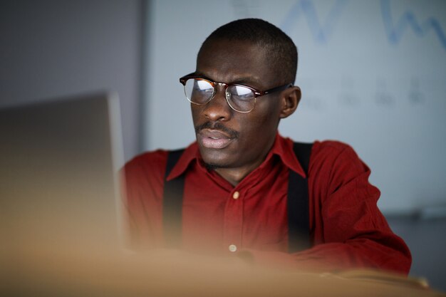 Empresario africano usando laptop en la oscura oficina