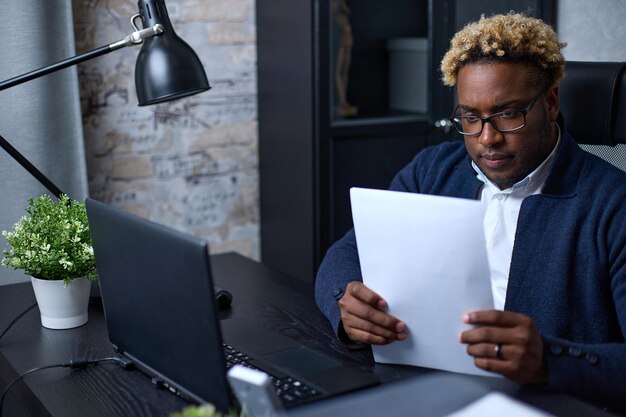 Empresário afro-americano examina cuidadosamente os documentos contábeis