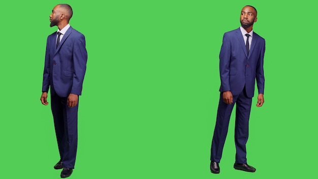 Empresário afro-americano olhando ao redor no estúdio, esperando por algo e vestindo terno de escritório. Funcionário formal de inicialização agindo com confiança posando sobre o pano de fundo de tela verde de corpo inteiro.
