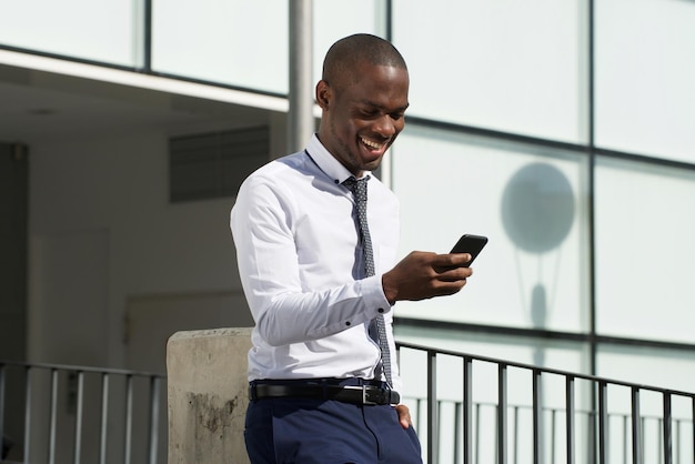 Empresário afro-americano olhando para o celular na cidade