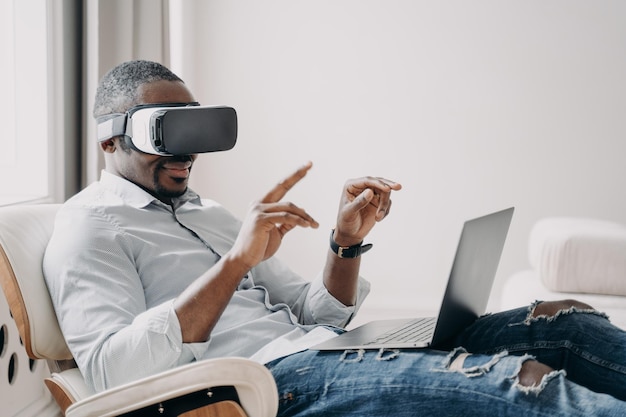 Empresario afroamericano en gafas de realidad virtual se sienta en la computadora portátil Tecnología futura de alta tecnología