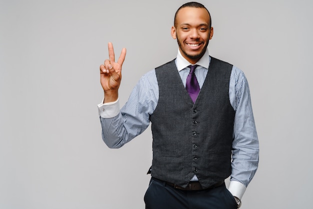Empresario afroamericano mostrando dos dedos sobre pared gris