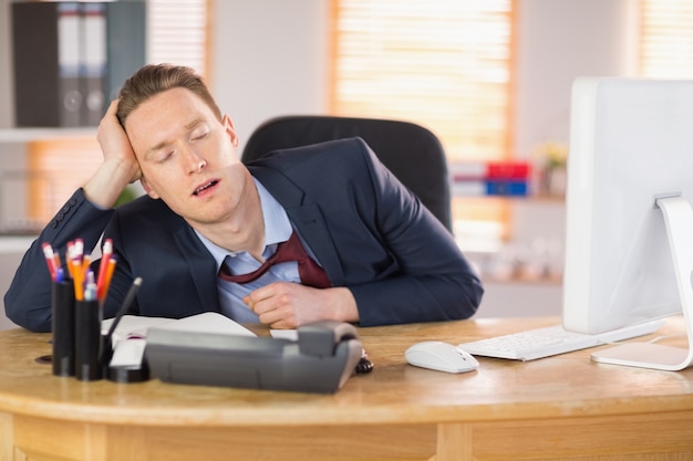 Empresario agotado durmiendo en su escritorio