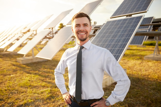 Empresario alegre en campo con baterías solares