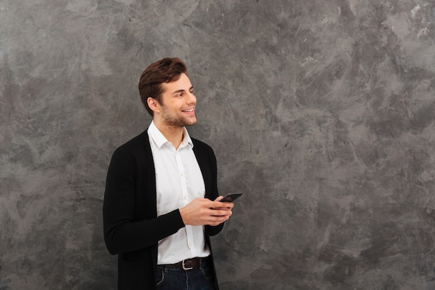 Empresario alegre chateando por teléfono móvil.