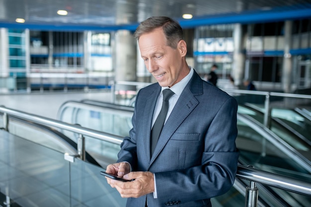 Empresario alegre leyendo un mensaje de texto en su celular