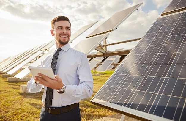 Foto empresário alegre usando tablet em prado com baterias solares