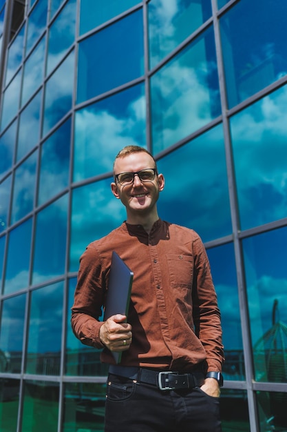 Empresário alegre vestido formalmente satisfeito com boas notícias recebidas sobre detalhes do contrato sentado no terraço do escritório com laptop empresário masculino de sucesso