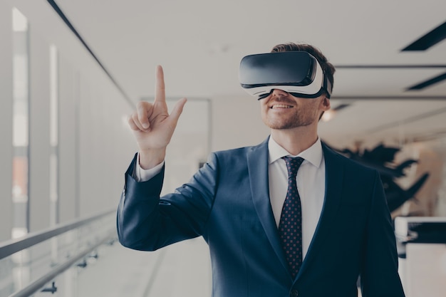 Empresário alegre vestido formalmente usando fone de ouvido vr no trabalho