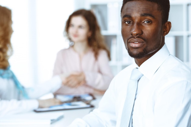 Empresário americano africano em reunião no escritório, colorido de branco. Grupo de empresários multiétnicos.