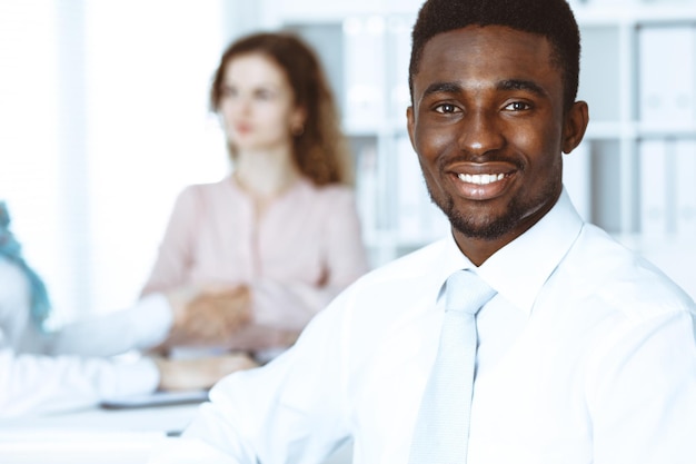 Empresário americano africano em reunião no escritório, colorido de branco. Grupo de empresários multiétnicos.